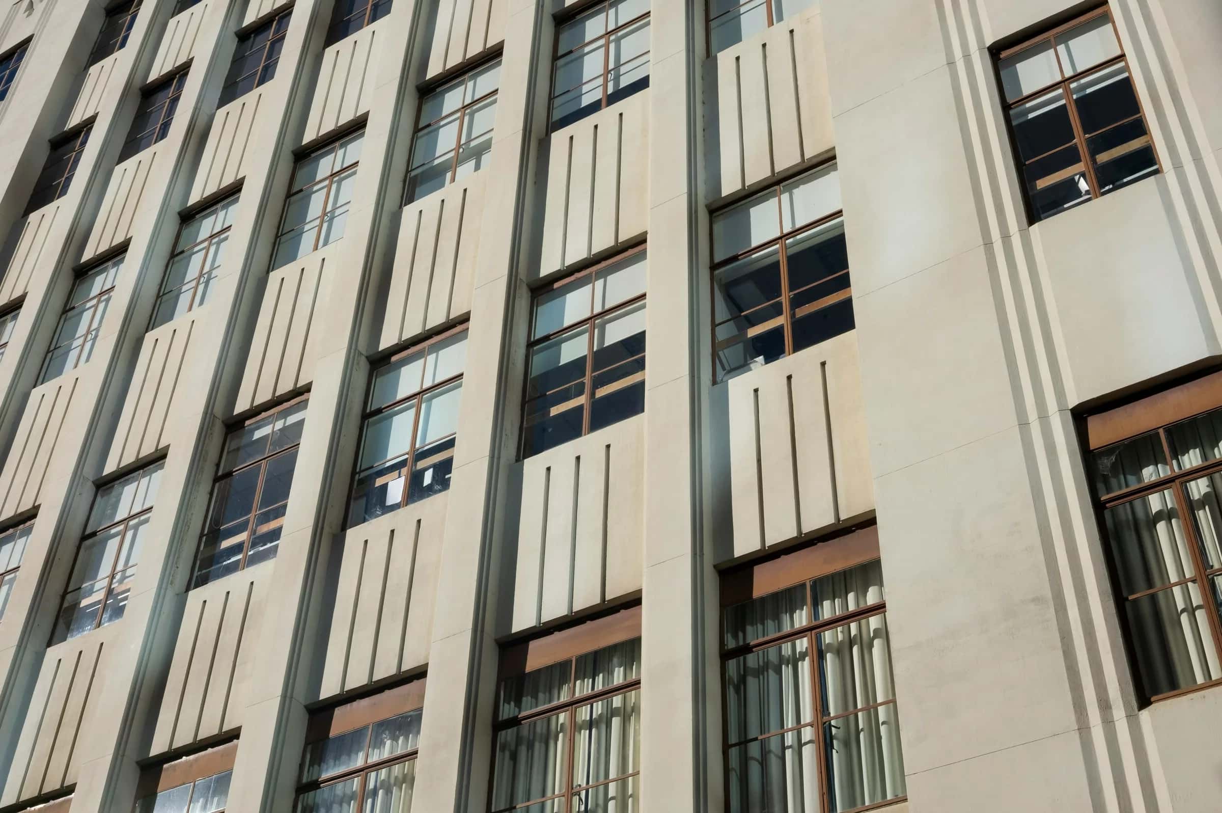 Beton bir binanın aşağıdan görünümü: tekrar eden dar pencere dizileri