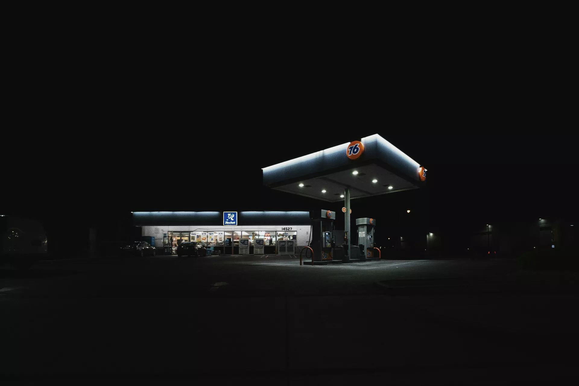 Gece ışıkları altında akaryakıt pompasında asılı duran tabanca