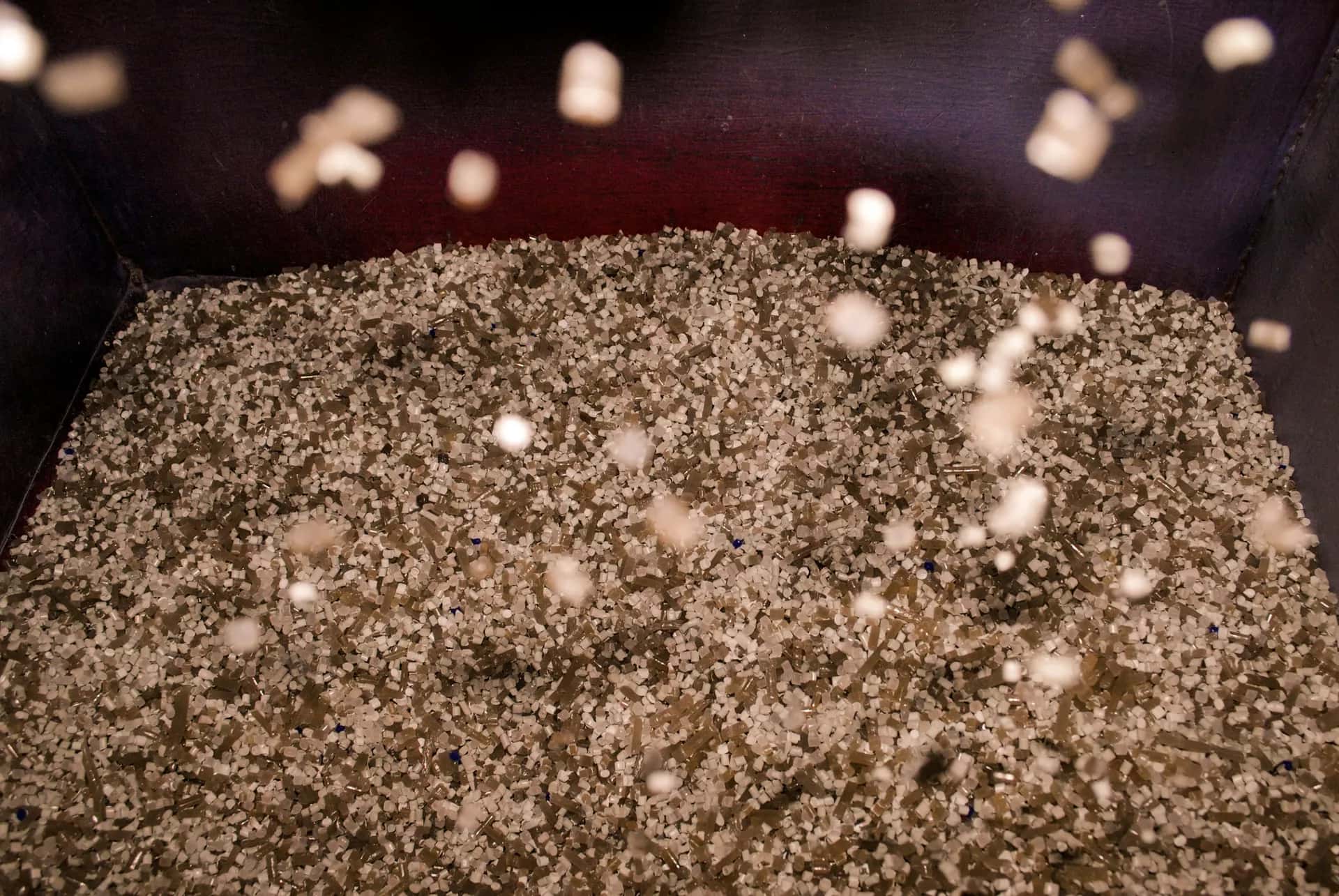 Metal bir kepçenin içinde yığılmış küçük plastik granüller