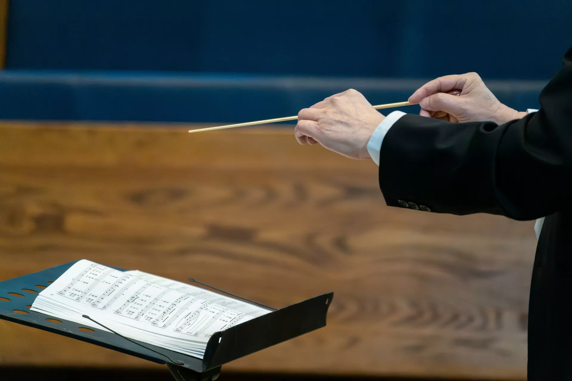 Nota kâğıtlarının üzerinde duran bir orkestra şefi batonu