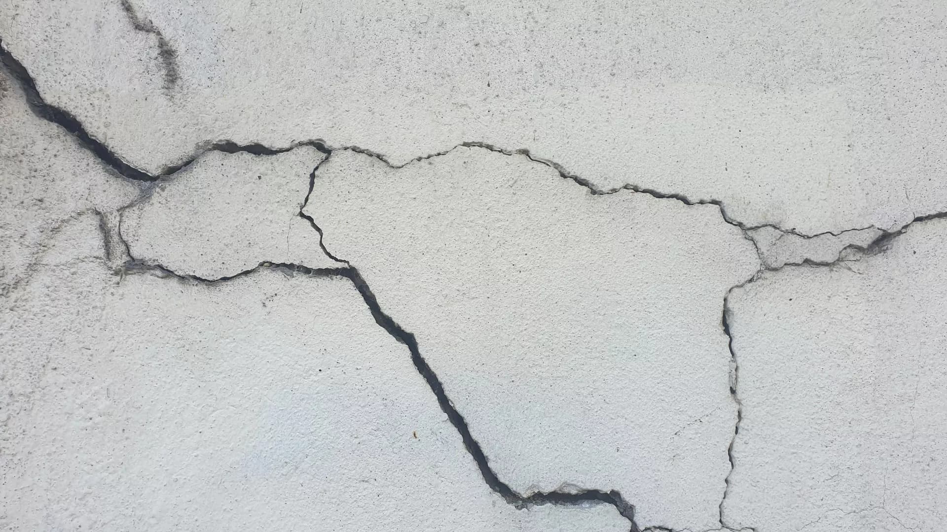 Eski bir binanın sıvası dökülmüş, çatlaklarla kaplı iç duvarı