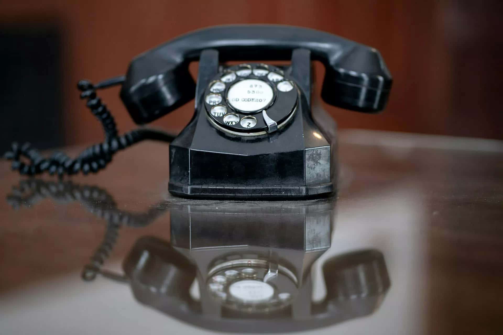 Ahşap bir masanın üzerinde duran eski tip çevirmeli telefon
