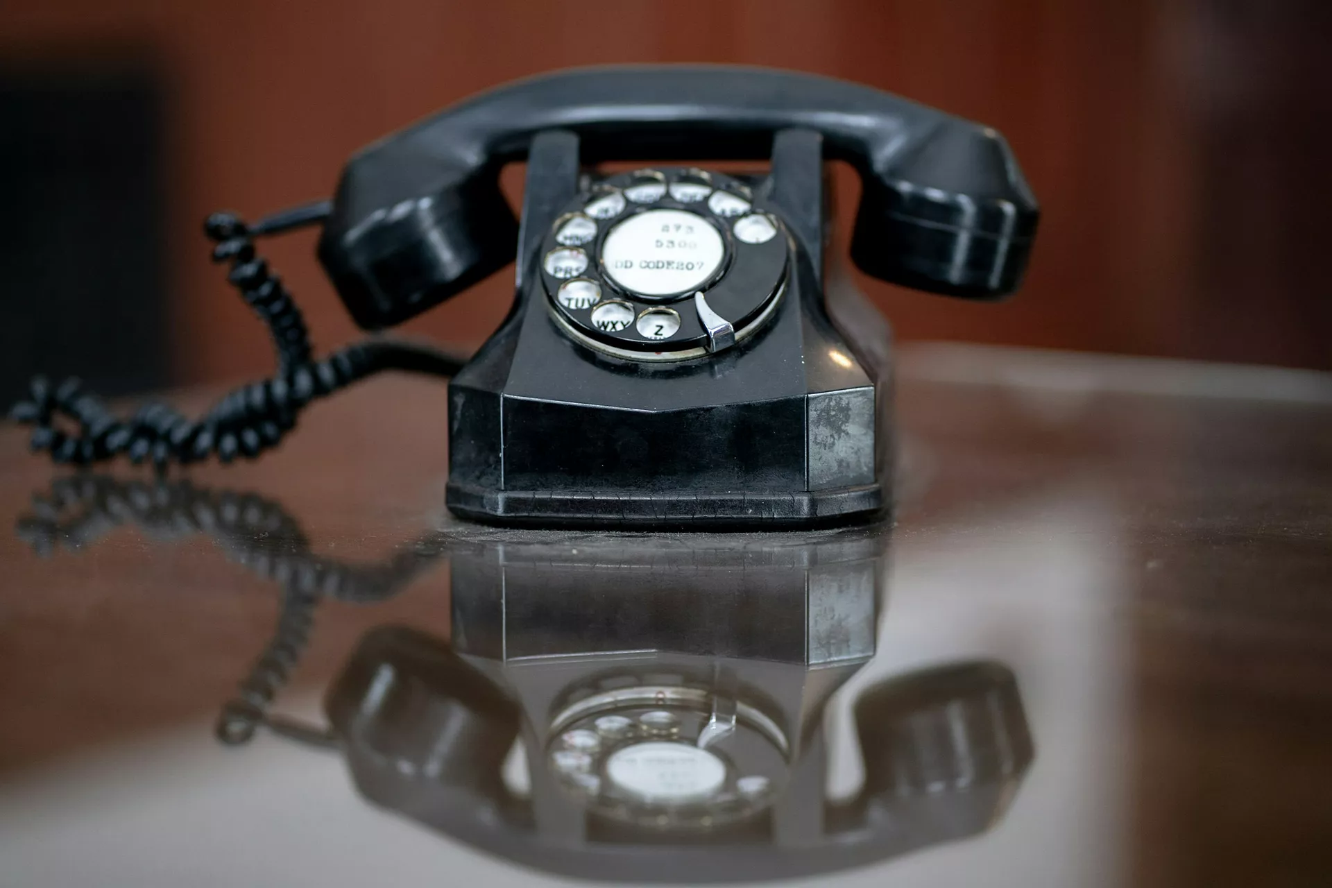 Ahşap bir masanın üzerinde duran eski tip çevirmeli telefon