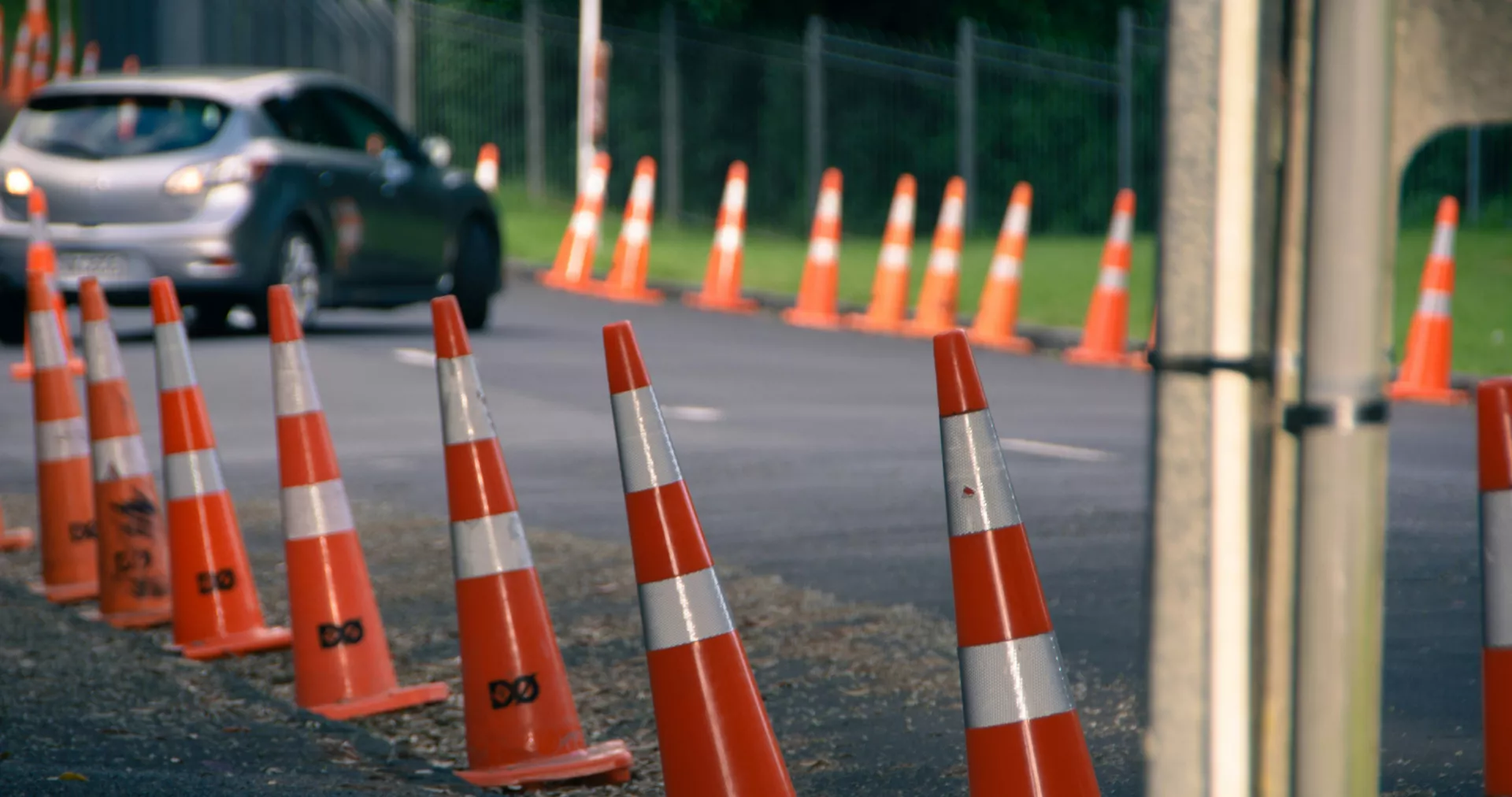 Asfalt yolun kenarında tek başına duran turuncu bir trafik konisi