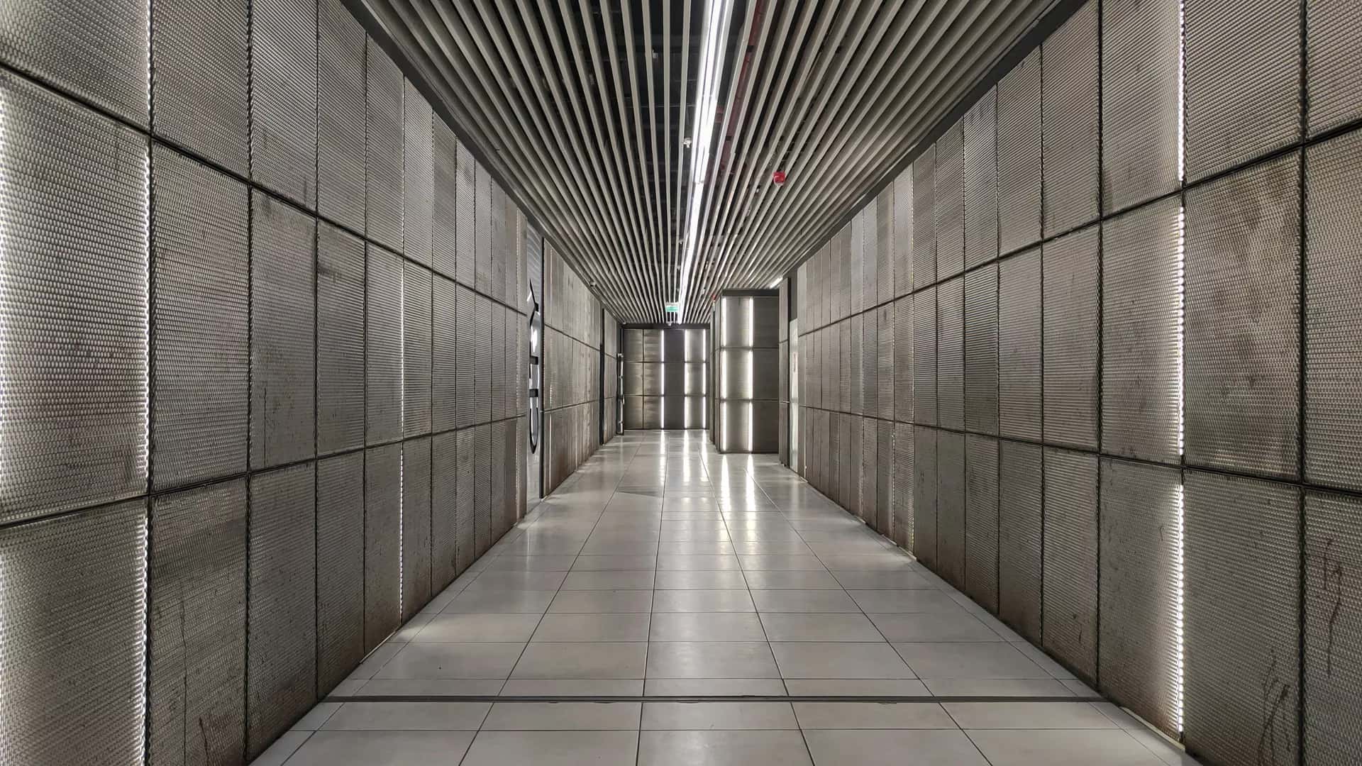 Beton bir binanın uzun, boş koridoru; sonda pencere ışığı